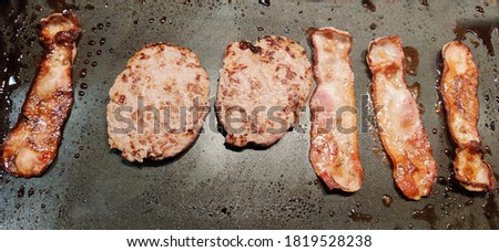 hamburgers and bacon cooking at the grill