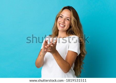 Young blonde woman isolated on blue background applauding after presentation in a conference