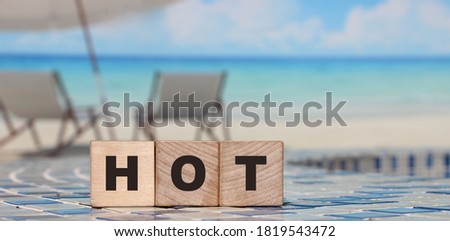 HOT word written on wooden blocks on ocean beach landscape. Vacation travel relax concept.