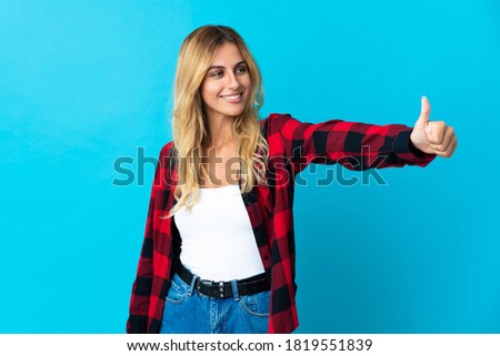 Young blonde Uruguayan woman over isolated background giving a thumbs up gesture
