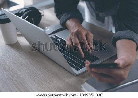 Business man online working on laptop computer and using mobile smart phone surfing the internet, close up. Male freelancer, entrepreneur working at home office, E-business and technology concept
