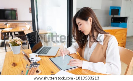 Portrait of female concentrating on her work with books, laptop and supplies on worktable in the office.