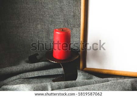 Candle and frame on a gray background. Red candle