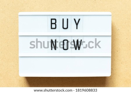 Lightbox with word buy now on wood background