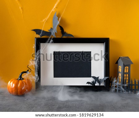 Happy halloween holiday concept. Black frame on orange background. Halloween decorations, pumpkins, bats, black frame. Halloween party greeting card mockup with copy space. 