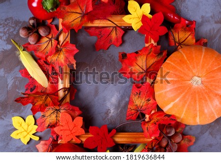Autumn background with the picture frame, decorative fallen leaves and pumpkin shaping the copy space