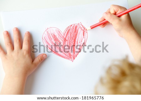 Close-up of childs hands drawing a red heart