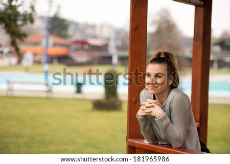 Fashion picture of a young beautiful woman leaned against wooden gazebo
