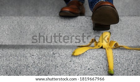 Accident in Daily Life Concept. Man Stepping Down Stair on a Banana Peel. Insurance or Business Metaphor Royalty-Free Stock Photo #1819667966