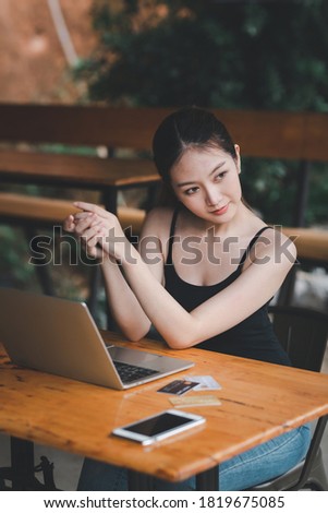 Portrain of Asian girl social media Searching for information using the Internet from a smart phone and laptop computer on wooden table