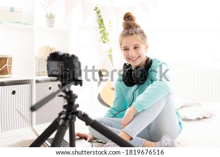 teenage blogger girl filming herself on camera in bright room