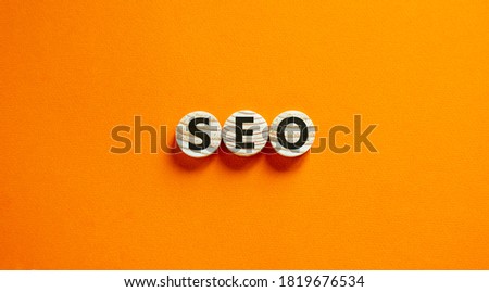 Concept word 'SEO' on wooden circles on a beautiful orange background. Search engine optimization. Copy space.
