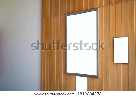 Mock up blank poster frame hanging on wooden wall in room.