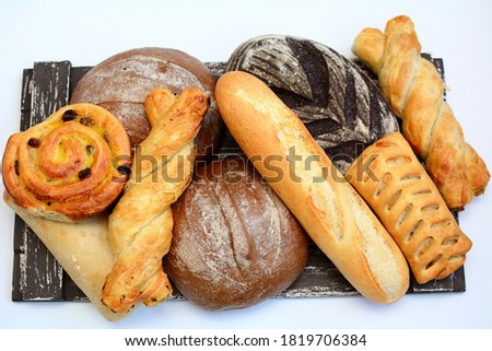 Different types of bakery products on a wooden tray on a white background. Top view