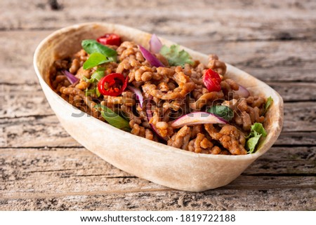 Mexican barquita taco with beef, chilli, tomato, onion and spices on wooden table