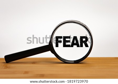 Focused on business concept. Magnifier glass with word FEAR First Encounter Assault Recon on wooden table. Business concept. Search idea