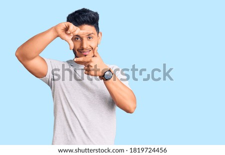 Handsome latin american young man wearing casual tshirt smiling making frame with hands and fingers with happy face. creativity and photography concept. 