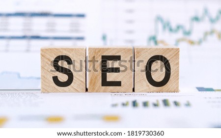 Wood cubes with the word "SEO", close up picture on financial charts background. Search engine optimization.