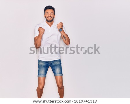 Young handsome hispanic man wearing casual clothes smiling happy. Jumping with smile on face celebrating with fists up over isolated white background