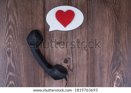 Telephone receiver with balloon bubble and red heart on wooden background. Confession, conversation of lovers, love, St. vylentin's day congratulations