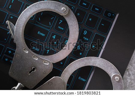 Handcuffs on a laptop keyboard, close-up. Concept on the topic of punishment for fraudulent activities in the digital space