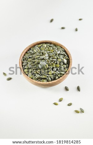 Pumpkin shelled dried seeds or pepitas in a wooden bowl. Healthy additive concept.