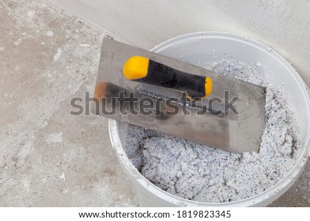 Spatula in a bucket with decorative mineral plaster ready for use