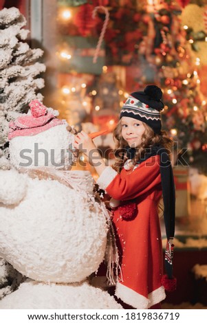 little girl makes a snowman on a snowy street
