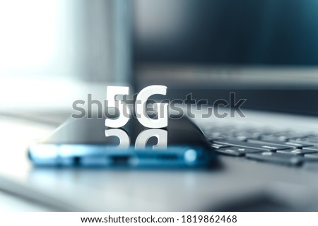 Mobile phone, smartphone with 5 G wireless high speed internet. Creative big white letters 5G on touch screen,reflection. Connection of cell, laptop for home, work, business.Modern technology concept. Royalty-Free Stock Photo #1819862468
