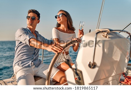 Group of friends relaxing on luxury yacht. Having fun together while sailing in the sea. Romantic couple sitting near steering wheel. Traveling and yachting concept. Royalty-Free Stock Photo #1819865117