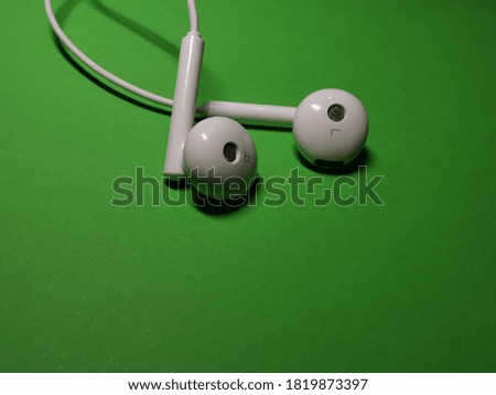 White earphones on a bright green  background. Use this photos for music, sounds, audio, privacy, and similar topics. 