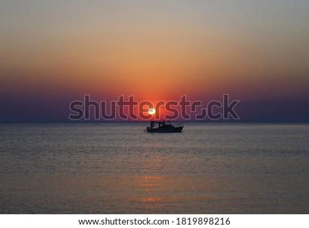 People admire the sea sunset while on board a pleasure boat. The evening sun hangs over the ship.