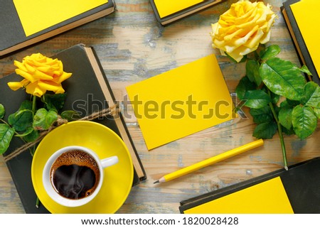 Bouquet of beautiful yellow roses with stack of old vintage books and hot coffee on wooden background. Copy space for nostalgic inscription. 
Flat lay, top view, copy space concept.
