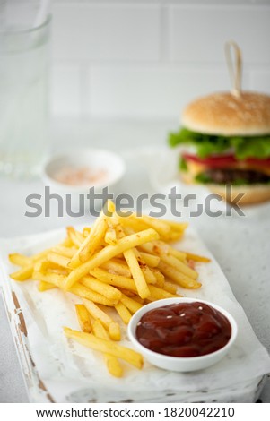 fries with tomato ketchup and hamburger on white table