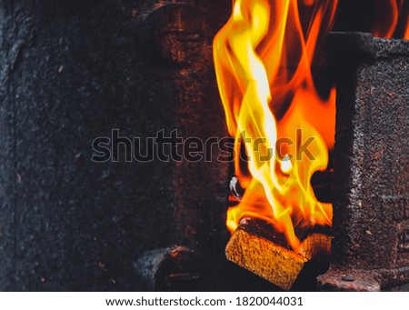 open door of a cast iron stove with a flame coming out from there
