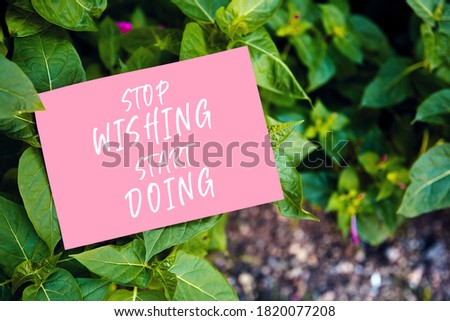Stop wishing start doing quote written on paper on green garden and leaf background. Taking action for achievement in business or life.