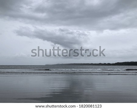 Atmosphere of curve dark clouds shadow sky reflection on the beach. Climate change shot. Storm sky against coast.
