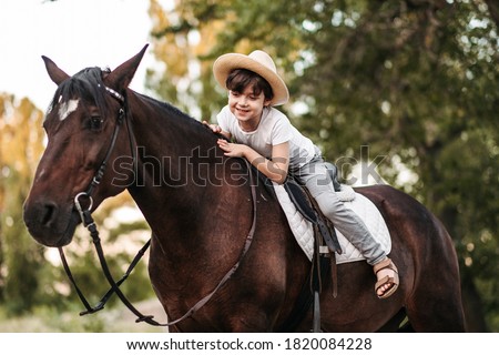 Boy with hat riding a horse outdoors. Pet therapy