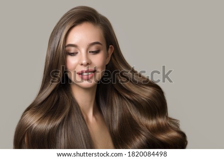 portrait of beautiful smiling brunette woman with wavy hair. Woman with hairstyle and makeup on gray background Royalty-Free Stock Photo #1820084498