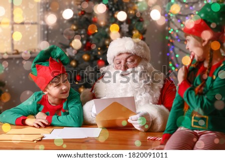 Elf kids with Santa Claus reading letter at home
