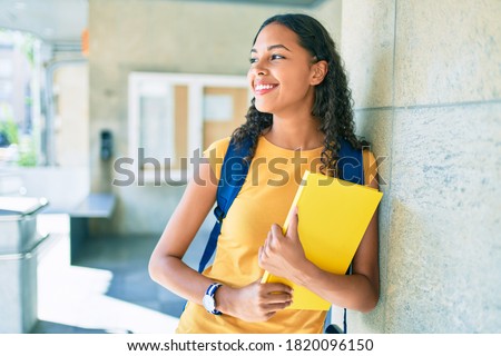 Young african american student smiling happy and holding book at university.