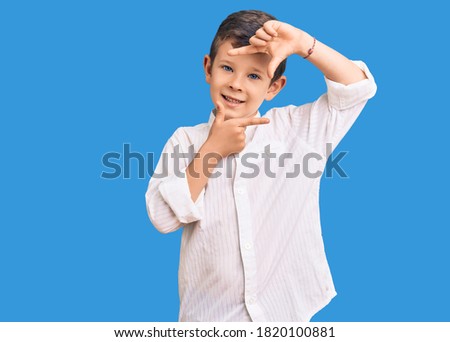 Cute blond kid wearing elegant shirt smiling making frame with hands and fingers with happy face. creativity and photography concept. 