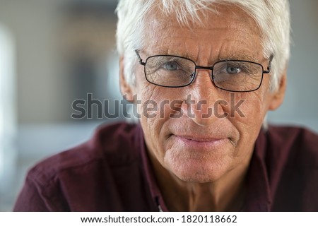 Portrait of smiling senior man looking at camera. Handsome old man with white hair wearing eyeglasses with satisfaction. Close up face of proud and satisfied mature male sitting on couch. Royalty-Free Stock Photo #1820118662