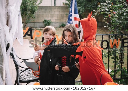 Costumed kids trick-or-treating on halloween decorated house and a USA flag on background
