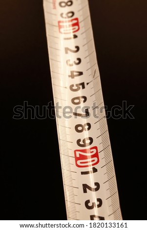 Close-up photograph of a roll-up metal meter strip with the measurement in centimeters,