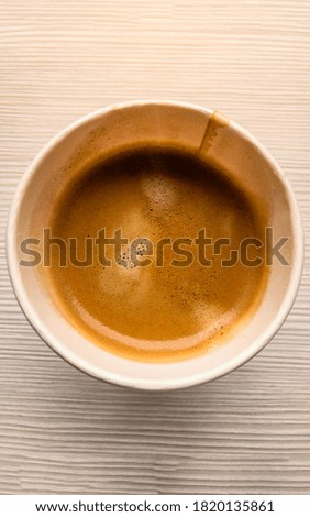 Top view hot coffee in paper cup or takeaway cup on table, close up to coffee in paper cup, vertical image, warm light tone.
