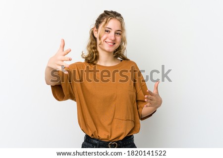 Young caucasian woman on white backrgound feels confident giving a hug to the camera.