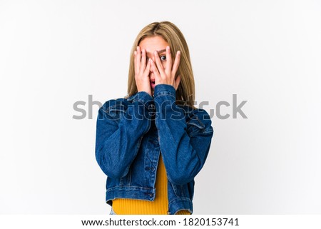 Young blonde caucasian woman isolated blink through fingers frightened and nervous.