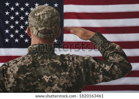 Soldier in uniform against United states of America flag, back view