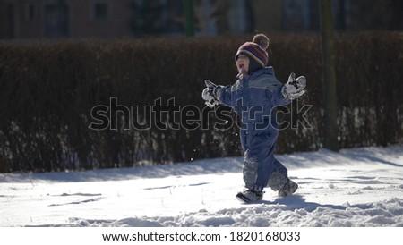 Funny child rise up from ground and run, snowed winter park Royalty-Free Stock Photo #1820168033